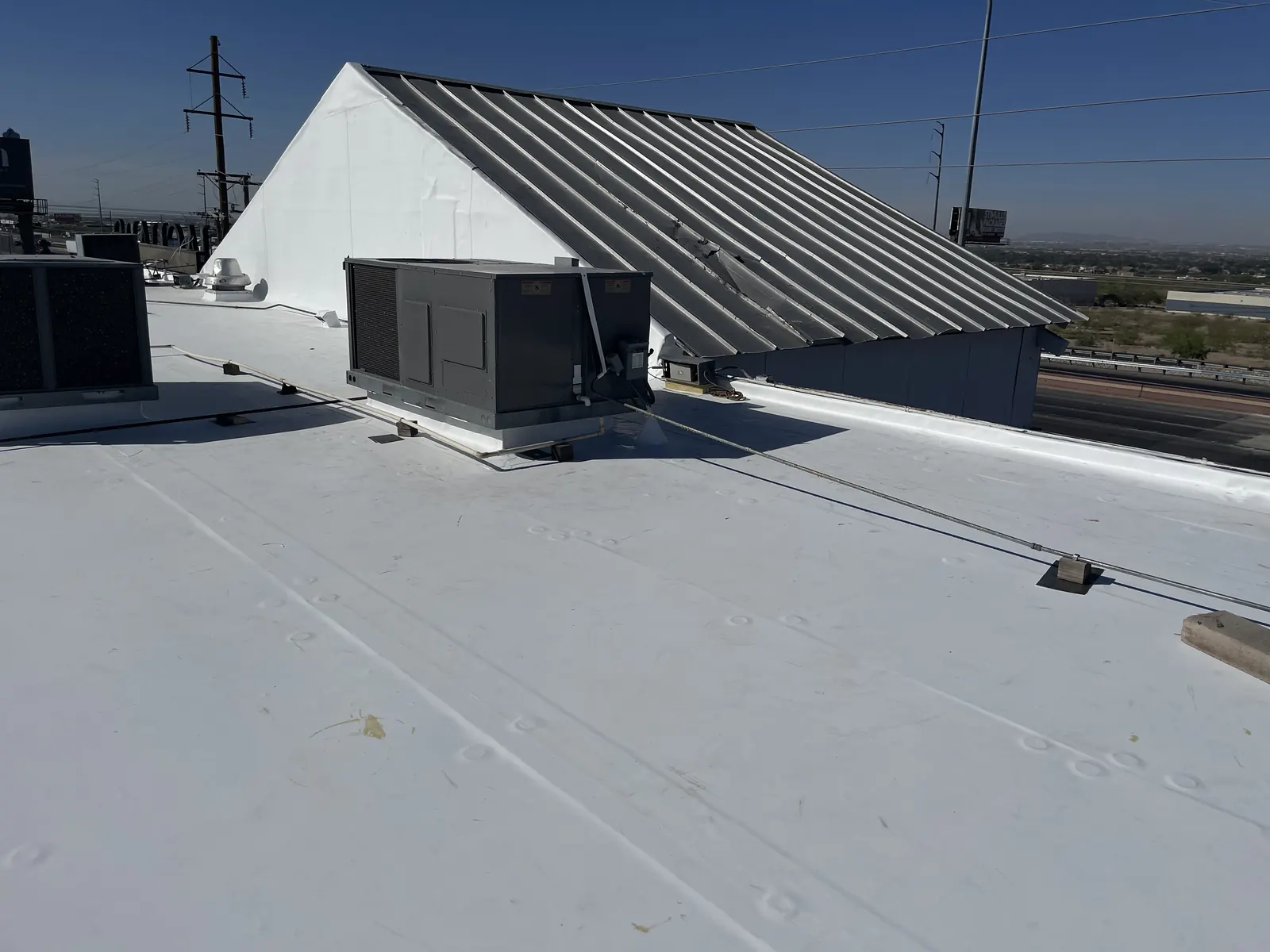 Mechanically attached TPO roof meeting a standing seam metal roof section with rooftop unit
